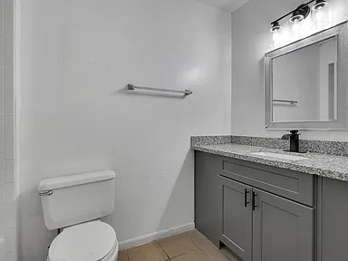 Bathroom vanity with granite counter, gray cabinetry, and mirror